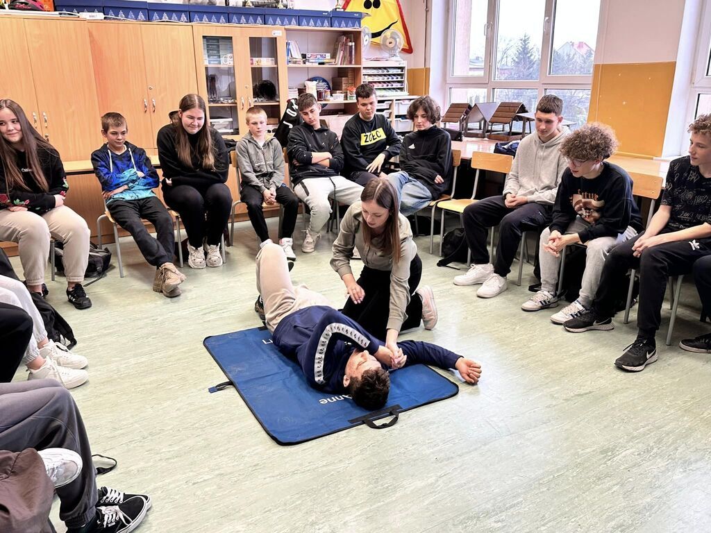 Uczennica liceum prezentuje prawidłowe ułożenie poszkodowanego w pozycji bocznej bezpiecznej